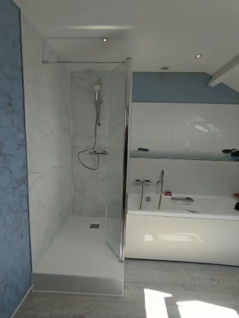 Douche vitrée à parement imitation marbre, à côté d’une baignoire