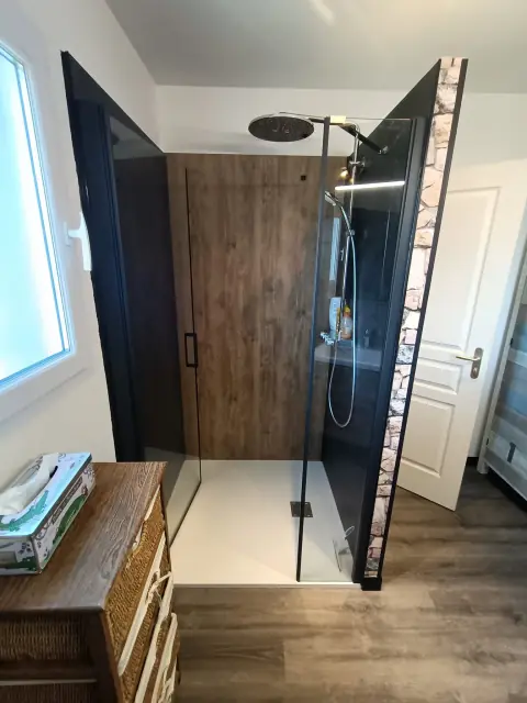 Douche à paroi vitrée à profilé noir, panneau mural imitation bois, douche de tête et receveur blanc
