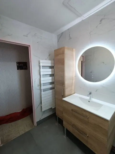 Meuble vasque en bois et colonne, miroir rond rétroéclairé, sèche-serviettes blanc et murs imitation marbre